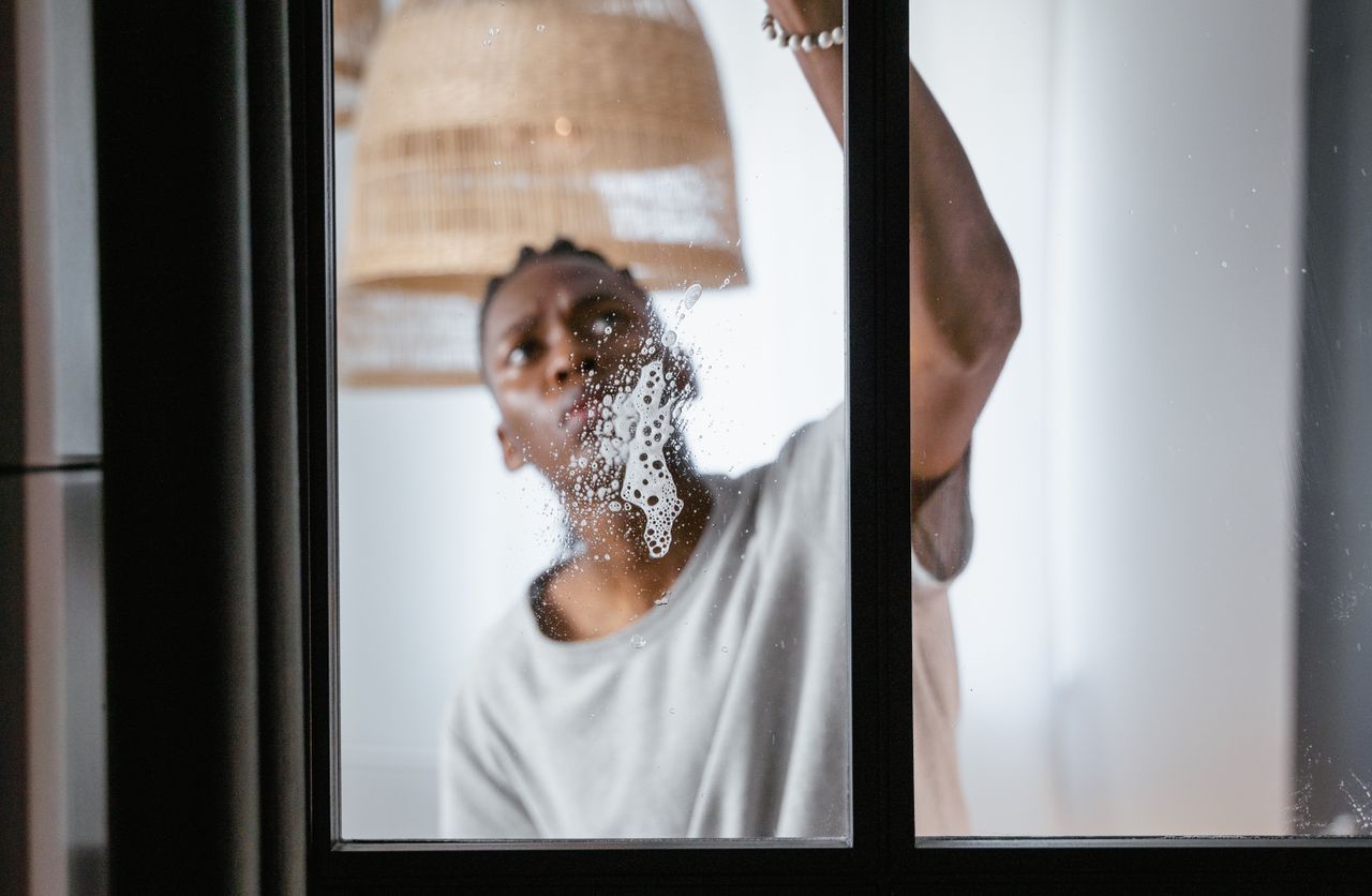 mobile-02 An adult male cleaning a glass window indoors, focusing on household chores and cleanliness.